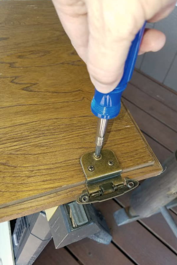 Remove the old hardware on the cabinet door and fill holes with wood filler before painting.