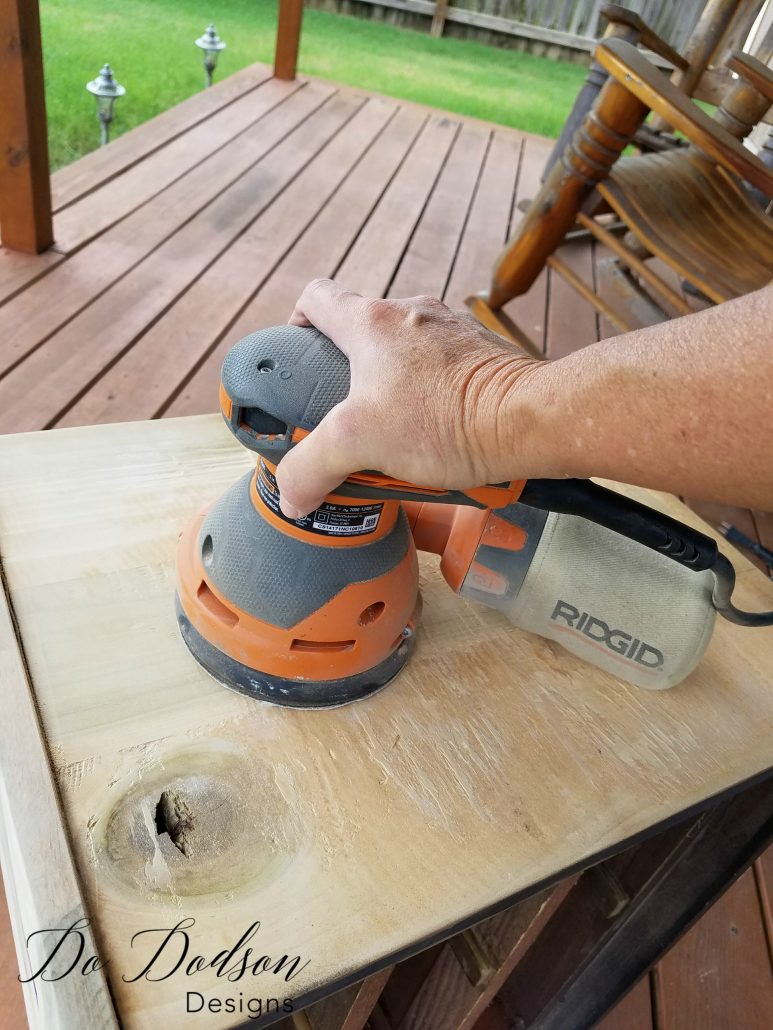 Sanding the wood under veneer that was removed on a Veneer Removal on a Dixie Nightstand / Painted Furniture Makeover