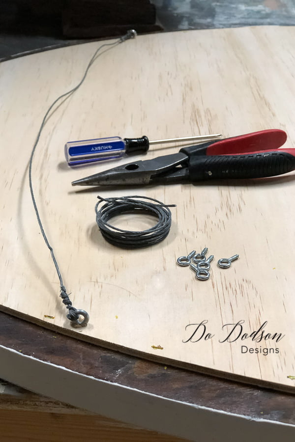 After the backing was applied to the reclaimed wood sign, I used eye screws and wire to create the hanger.