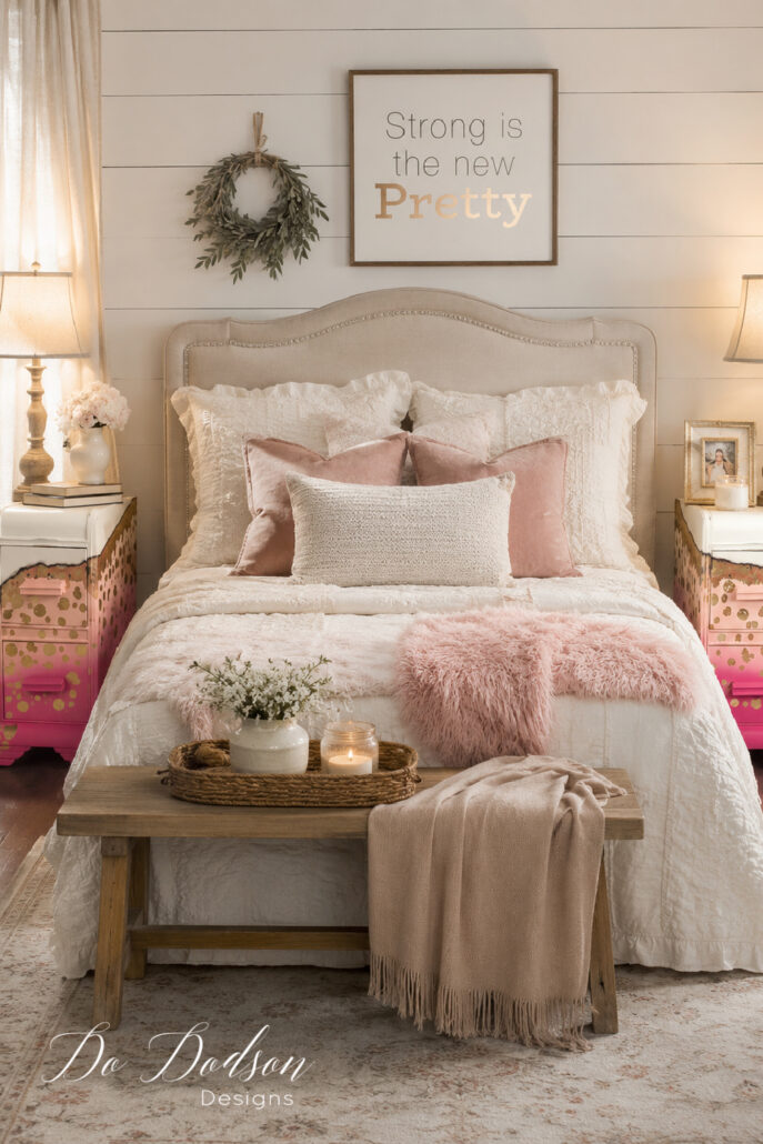 Whimsical DIY painted nightstand with a pink ombr&eacute; finish and gold accents styled beside a cozy neutral farmhouse bed.