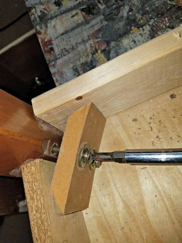 I removed the broken piece of particle board and staples, cleaned up the surface, drilled two holes for screws to secure it to the table with my Ryobi Lithium-Ion Drill, added wood glue to all the ends that connected with the table, reattached the screws that secured the leg back into place. Good as new!