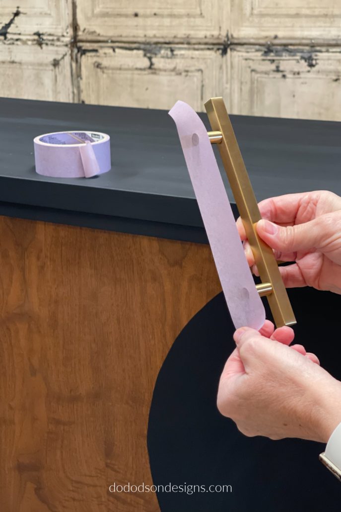 Apply the painter's tape across the back of the hardware lengthwise from tip to tip. This will ensure that you have the exact same length and will help with the placement of the hardware on your dresser/cabinet.