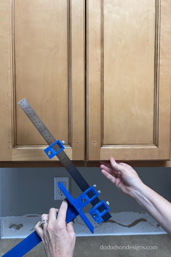 I used a cabinet hardware jig to get the perfect placement of my new kitchen cabinet hardware. Long modern pulls are perfectly aligned.