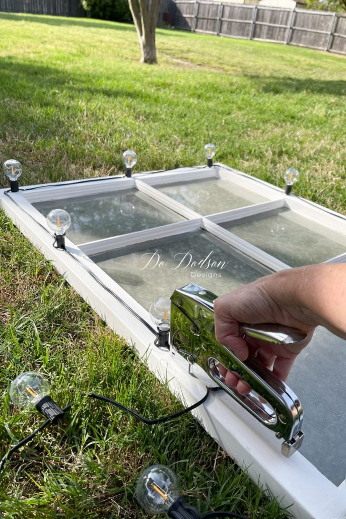 Secure the string lights the the old window with a staple gun for an instant outdoor lighting feature.