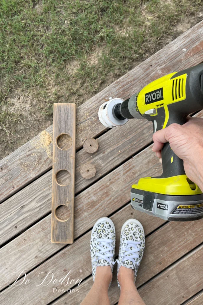 Once you have the wood, cut to size, measure where you want your wood vase holder opening to be; the best way to do this is to center the first vase on the board and then measure the placement for the other two with equal spacing. I used a pencil to mark the vase's opening and cut a hole using a hole saw. These holes will vary based on the hole saw bit that you have, but you can also use a jigsaw.