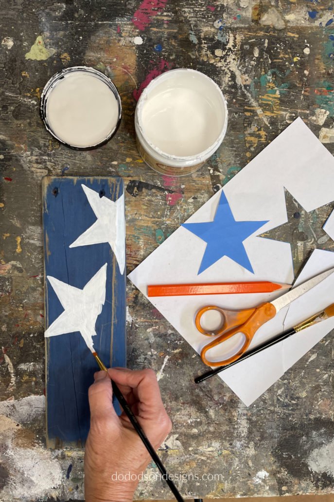 If you have a computer, create a word document and insert a star shape. Print it off on paper and cut it out with a pair of scissors. Lay the cut out of the star over your wooden firecrackers and trace around it with a pencil. I like using paper to make these simple stencils because it wraps around the sides easily.