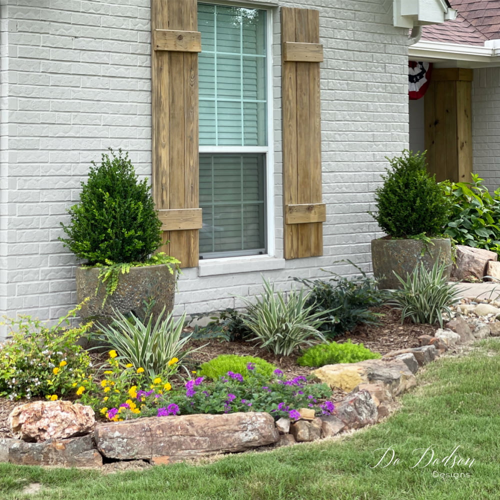 I love the look of painted brick with the warm wood tones and those rock borders in the flower beds make the natural elements cohesive.