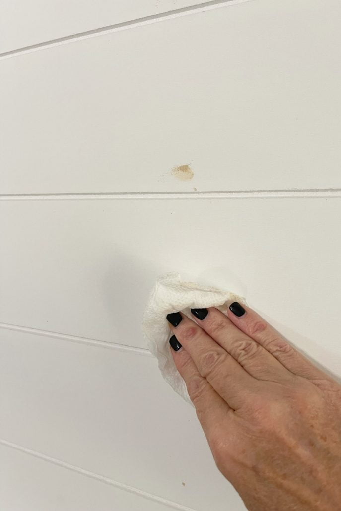 After applying the wood filler to the nail holes, remove the excess with a damp cloth. No sanding will be needed before painting the shiplap paneling.