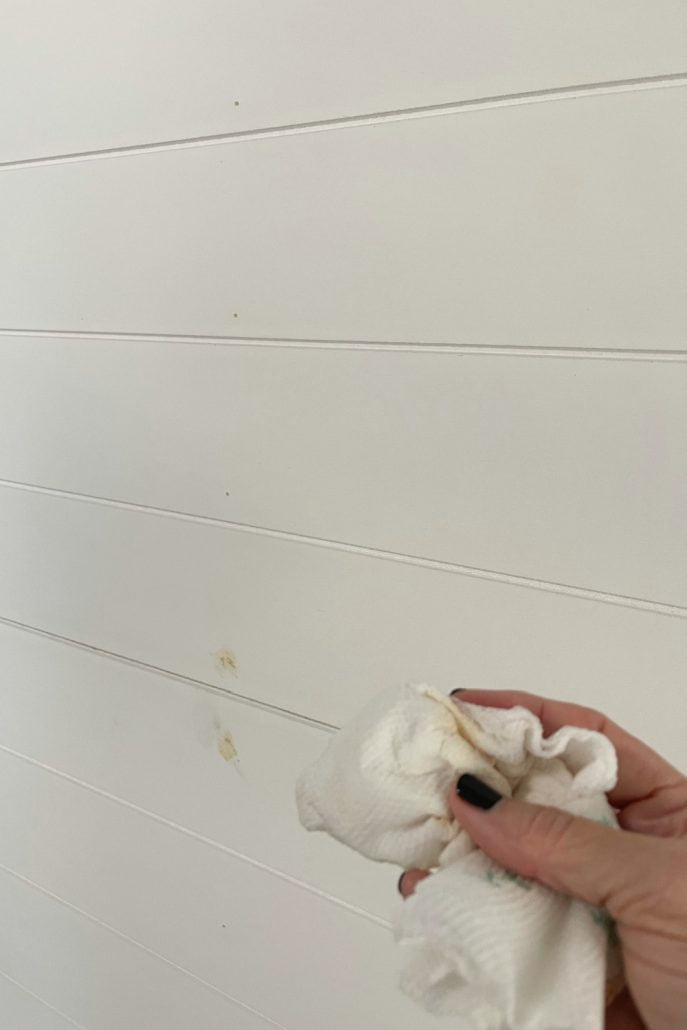 After applying the wood filler to the nail holes, remove the excess with a damp cloth. No sanding will be needed before painting the shiplap paneling.