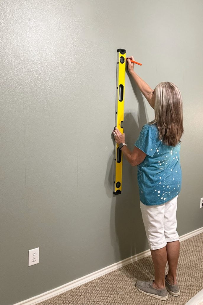 Mark the wood studs on the wall using a straight edge. Most walls are constructed with 2x4s and should be on 16-inch centers. That means there should be a 2x4 for every 16 inches. Find your first stud and measure over to the left or right, determine their location and mark them using your level, so they're visible above or below the paneling. Use a small nail to find the studs and then keep them in a straight line, so they are easy to see. The shiplap paneling will cover the lines, so there is no need to worry about messing up the wall.