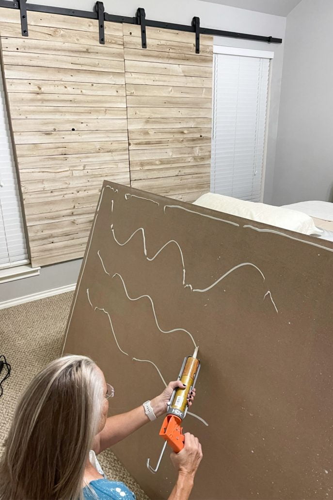 Apply liquid nail to the back of shiplap paneling before securing it to the wall.