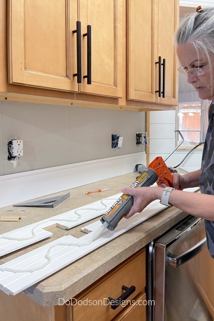 I used liquid nail adhesive to secure the shiplap board to the backsplash before a nailing them in place.