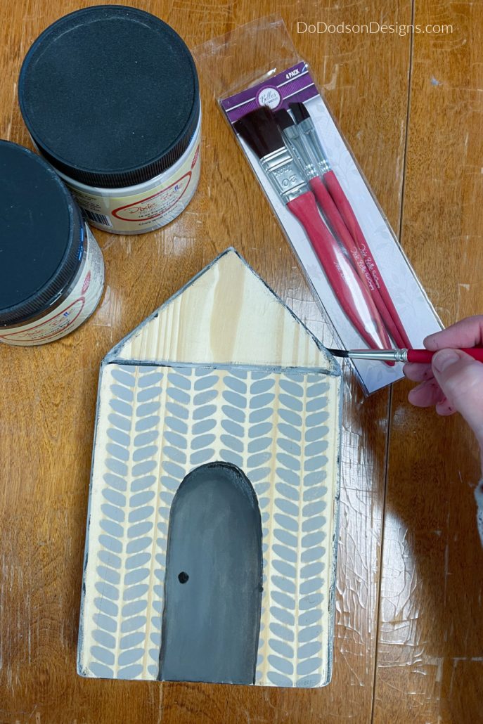 With a small artist brush, use a darker color to outline the door. Depending on how you want the light to reflect on your painted door, you use a dark color and blend the lighter color into the darker to give it depth. You can use a little water on the tip of your artist's brush to blend the paints into each other.