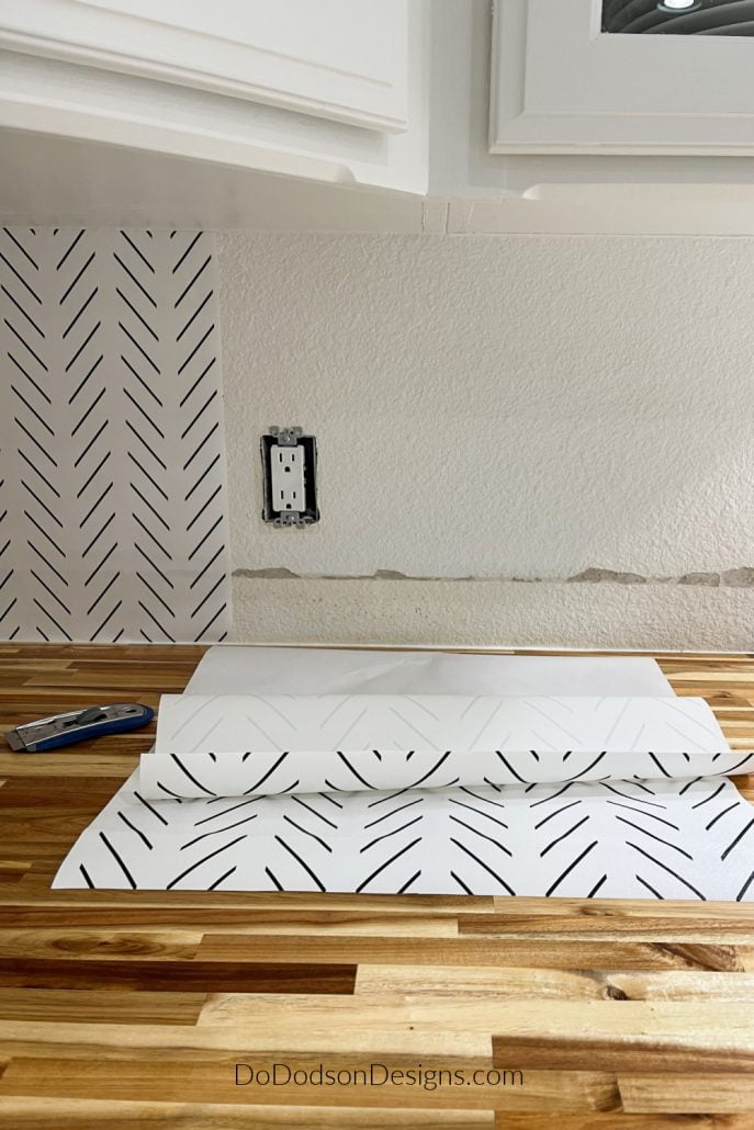 After cutting the wallpaper into the size strips you need, then peel away the back sheet to expose the sticky side of the peel and stick wallpaper about 1/3 of the way down. Don't try to remove the whole back sheet because I promise the results won't be good.