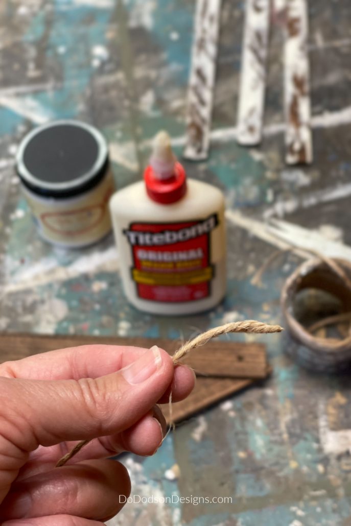 Here's a tip for getting jute twine through small holes when crafting. Use a dab of glue on the end of frayed twine and twisting it between your fingers. It's so much easier to feed through a hole.