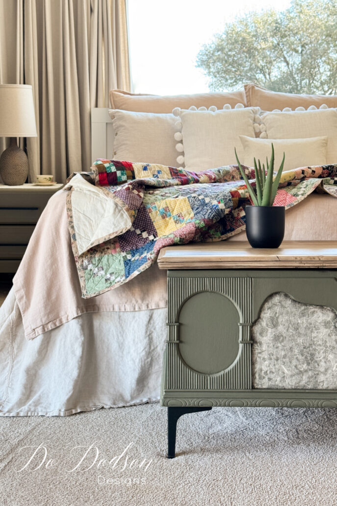 Vintage cedar chest painted green with vintage decoupage on the front, a light wood top, and modern black legs in a bedroom setting.