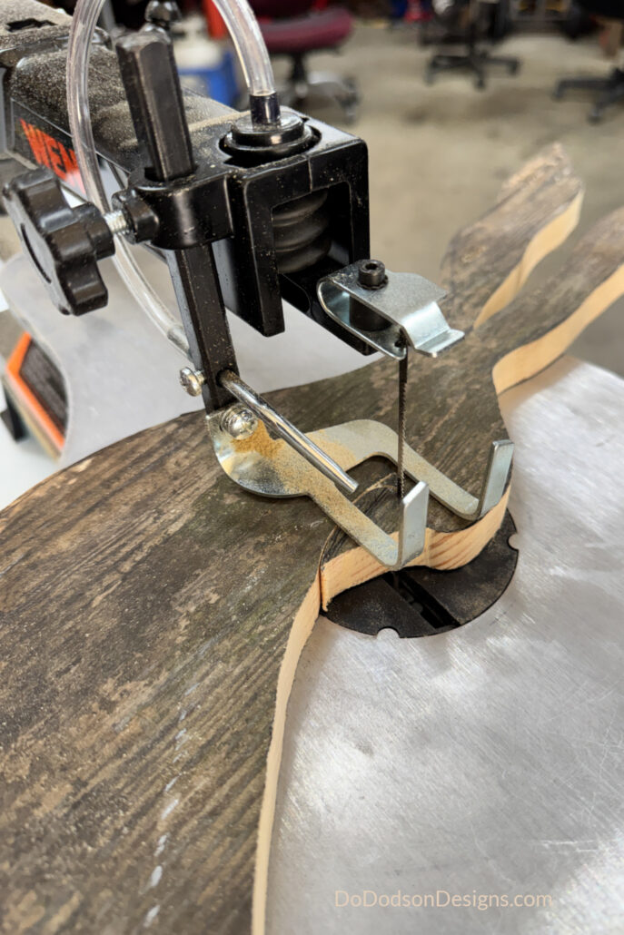 Scroll saw cutting a DIY wood Easter bunny shape from scrap wood, showing close-up of blade and curved cut lines in a woodworking project.