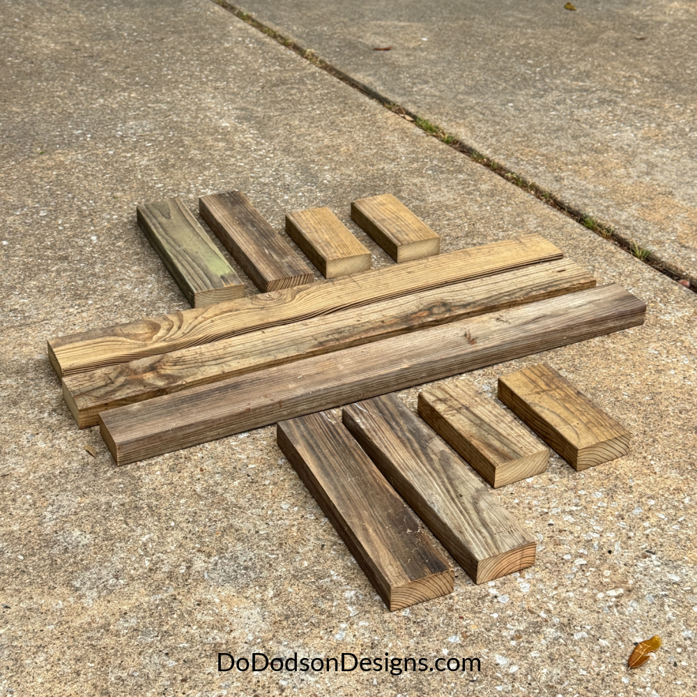 Cut 2x4 wood pieces laid out for a wood bench build, including 36-inch top boards, 14.5-inch legs, and 8-inch supports on a concrete surface.