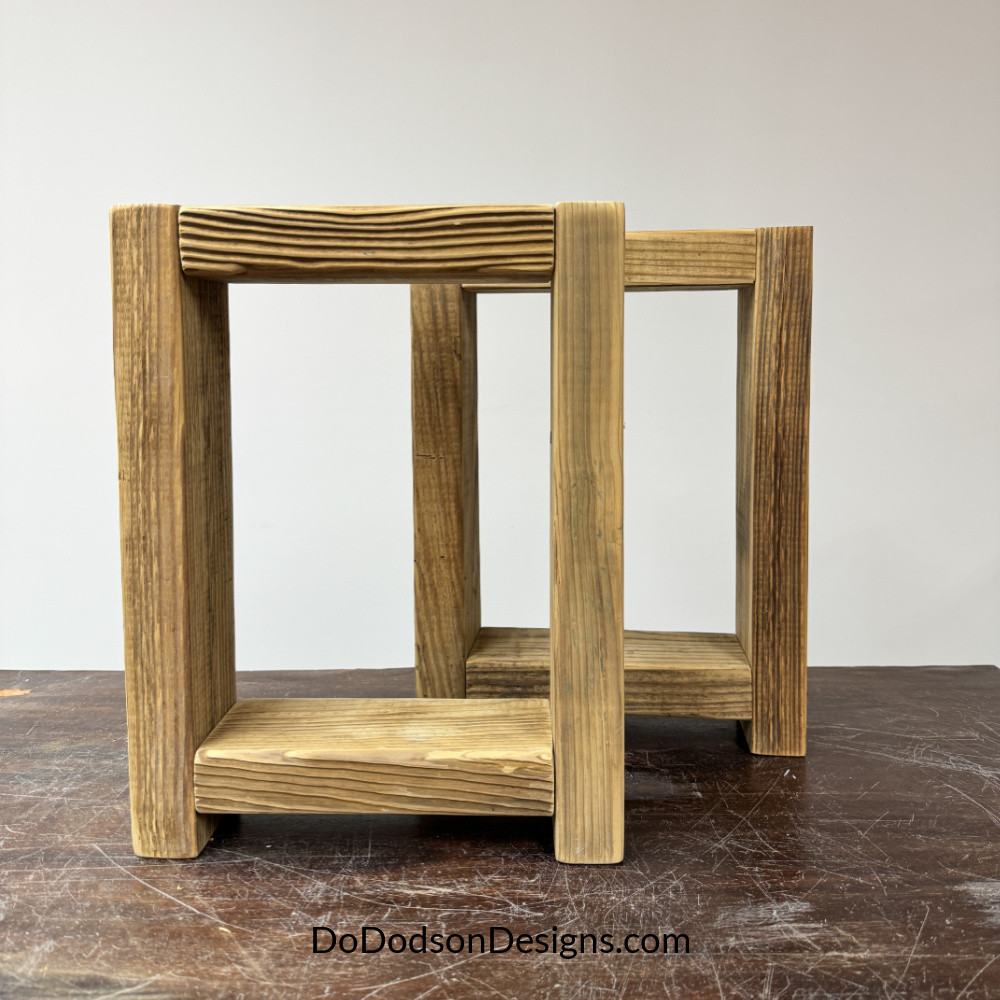 Two assembled side frames made from 2x4 lumber for a DIY wood bench, showing the rectangular leg structure before attaching the bench top.