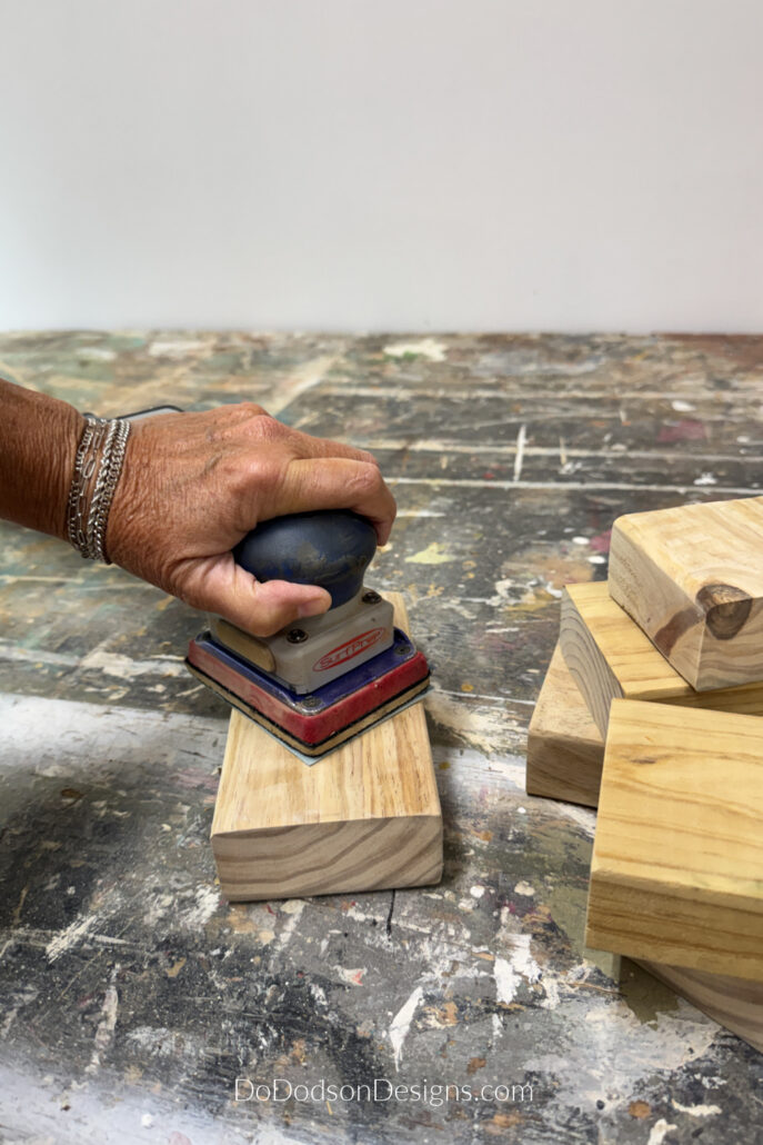 Hand sanding smooth wooden 2x4 blocks on a workbench while creating easy  wood block flags.