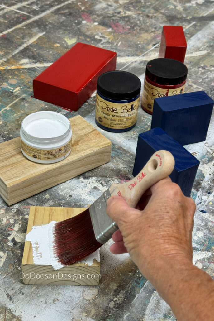 Painting scrap wood blocks in red, white, and blue using chalk paint for easy DIY wood block crafts and patriotic farmhouse-style 2x4 decor projects.
