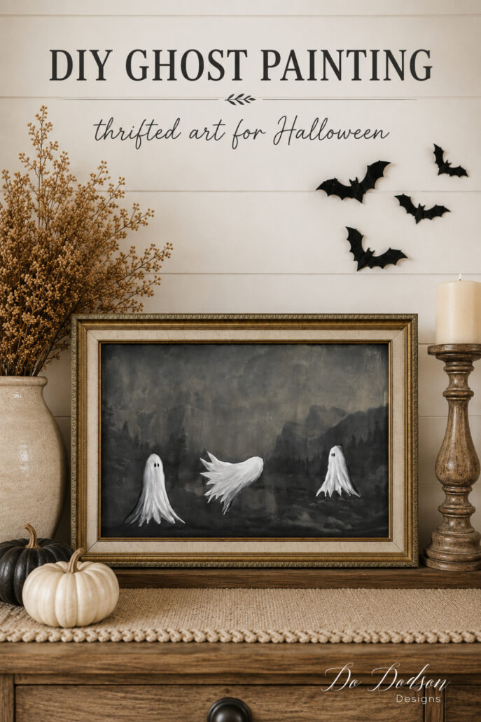 DIY ghost painting on thrifted landscape art displayed in a cozy neutral farmhouse Halloween vignette. 