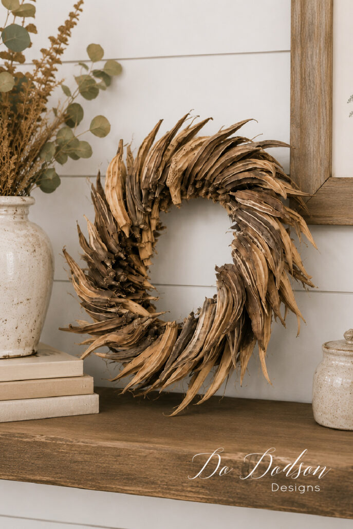 DIY dried okra wreath displayed on a rustic wooden shelf as cozy neutral farmhouse fall decor.