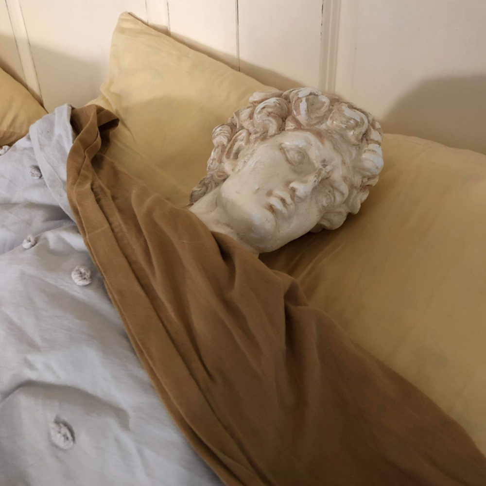 Thrift store Bust of David tucked into bed as a funny prank before his aged patina makeover.