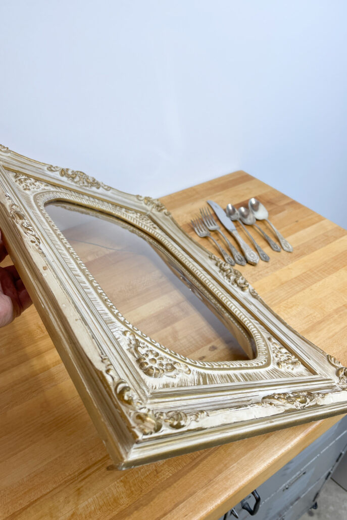 Vintage ornate picture frame with old silverware ready to be repurposed into unique farmhouse wall decor.