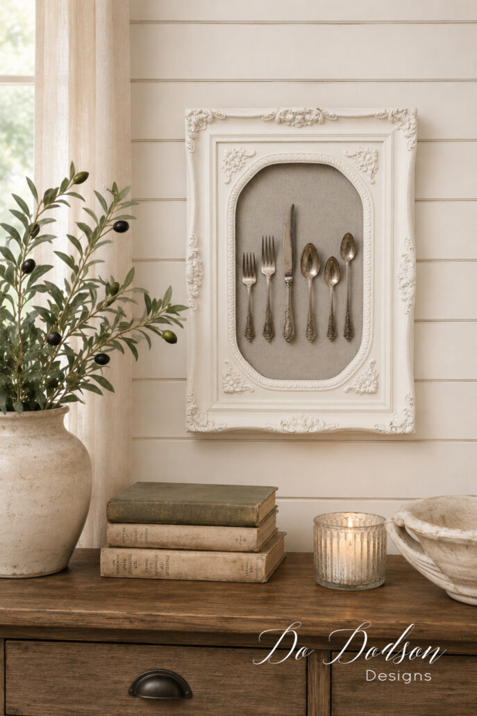 Repurposed ornate picture frame displaying vintage silverware, styled as unique farmhouse wall decor above a rustic wood dresser.