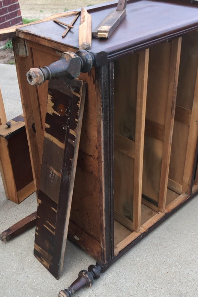 Broken vintage dresser with a damaged leg, missing drawers, and exposed wood before its secondhand furniture makeover.
