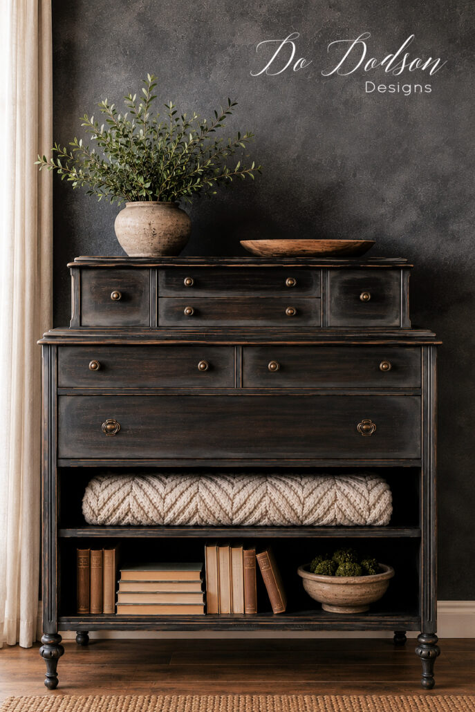 Restoration Hardware-inspired dresser makeover with a dark distressed finish, open shelving, neutral decor, vintage books, and a textured throw.