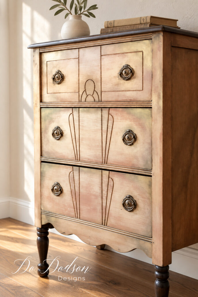Close angled view of the thrifted chest showing its aged metallic finish, decorative drawer details, and gilded hardware.