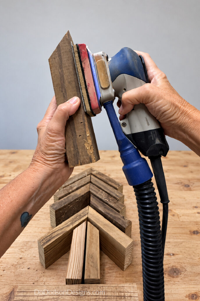 Sanding a cut 2x4 piece before assembling a scrap wood Christmas tree.