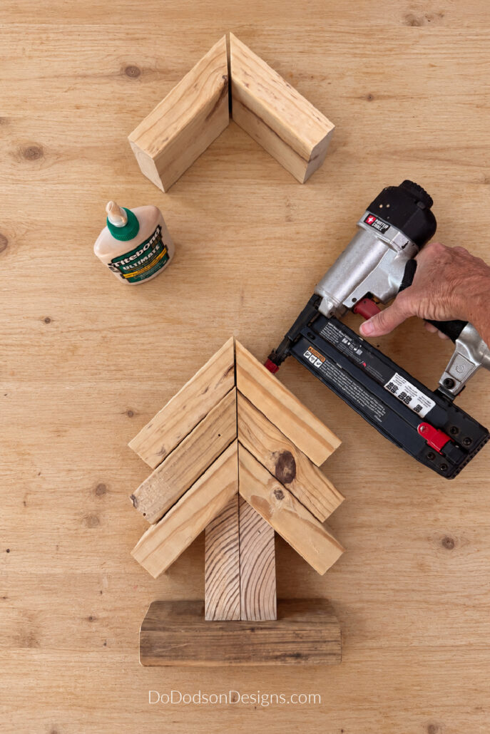 Securing a 2x4 scrap wood Christmas tree with a brad nailer.